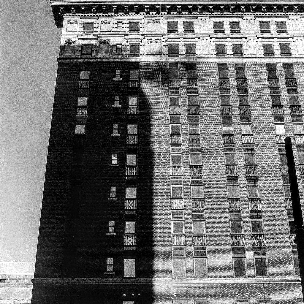 A black and white photo of a person waking in light and shadows.