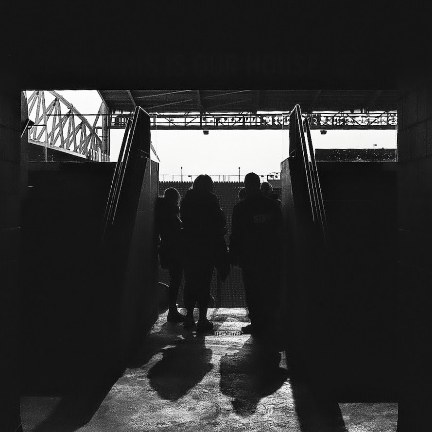 A black and white photo of a person waking in light and shadows.